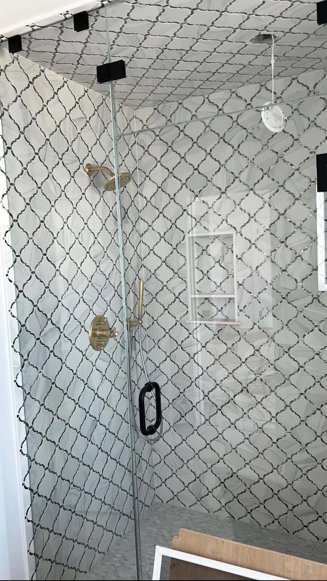 Arabesque tile shower wall with brass rainfall head and frameless glass