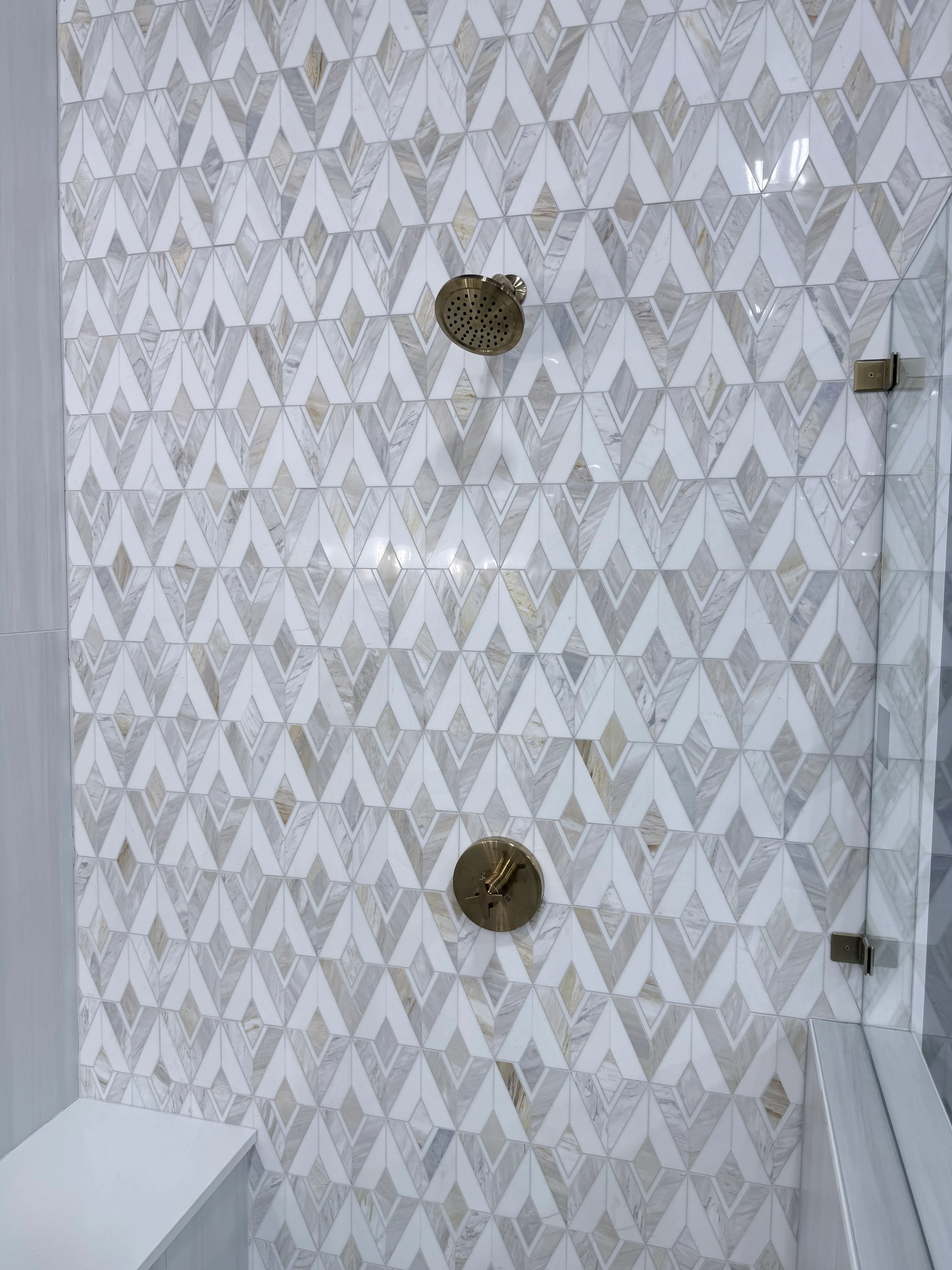 3D-effect geometric marble mosaic shower wall with brass fixtures