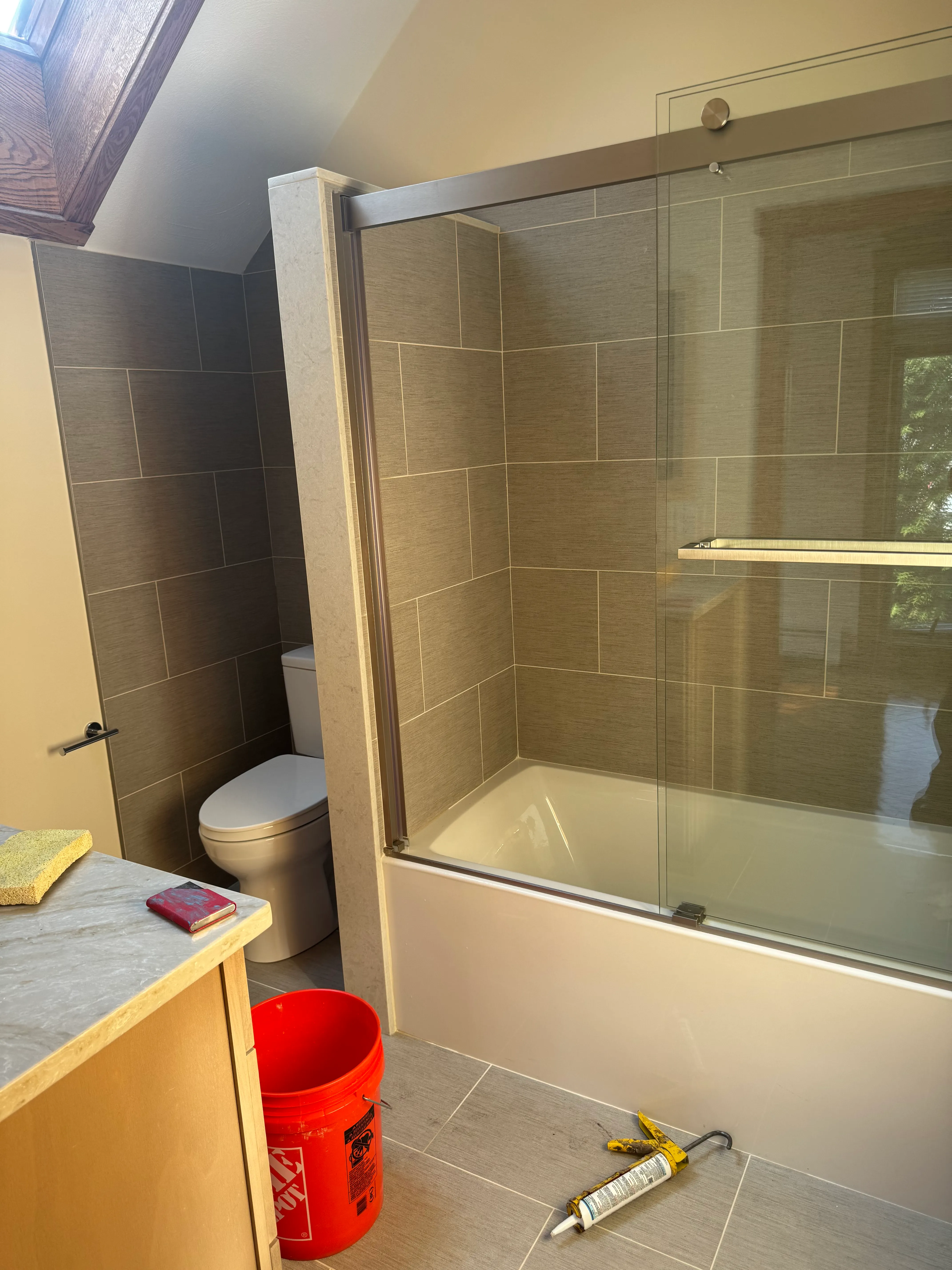 Standard glass shower enclosure with neutral tile, install in progress
