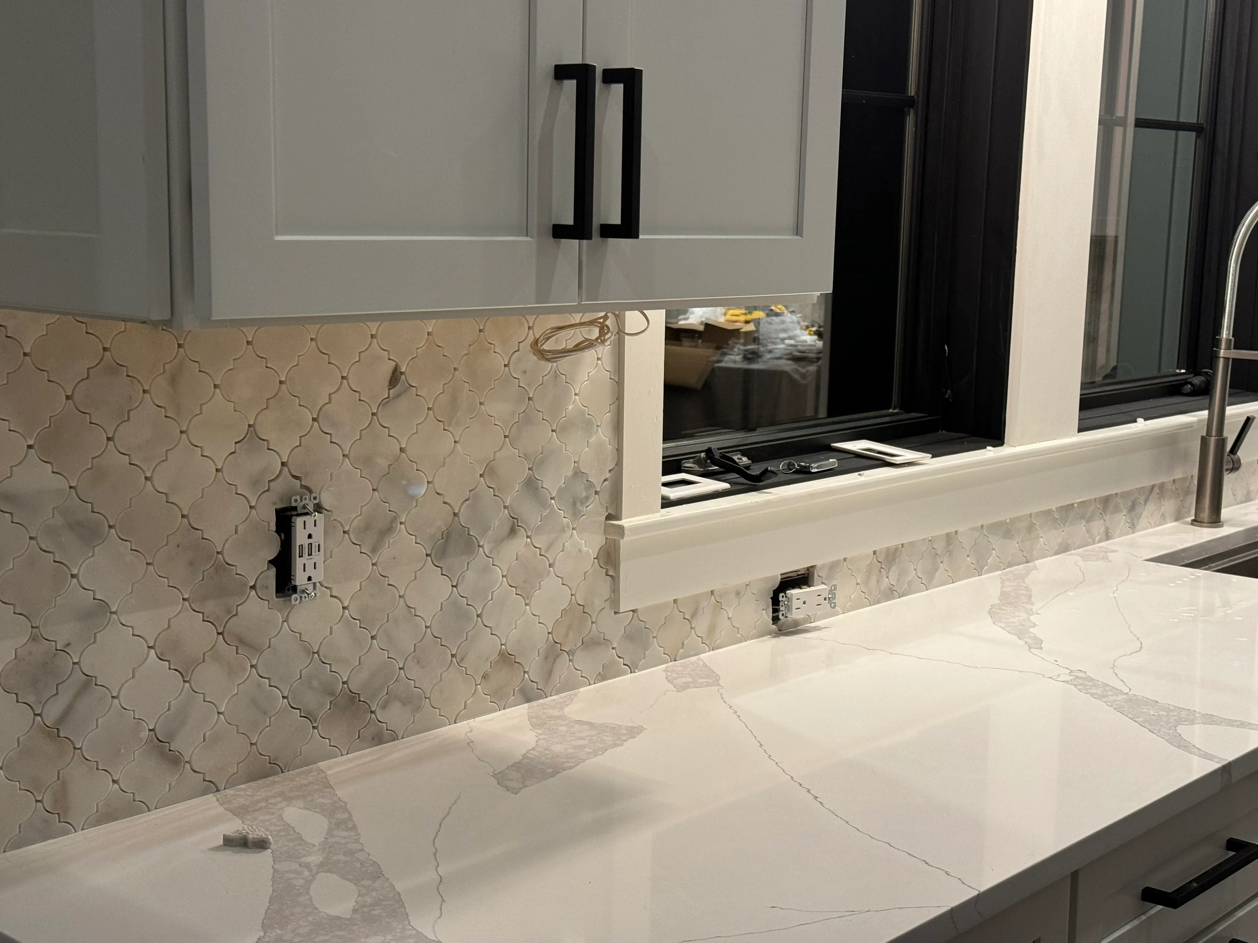 Kitchen with arabesque-tile backsplash, gray cabinets, and quartz countertops
