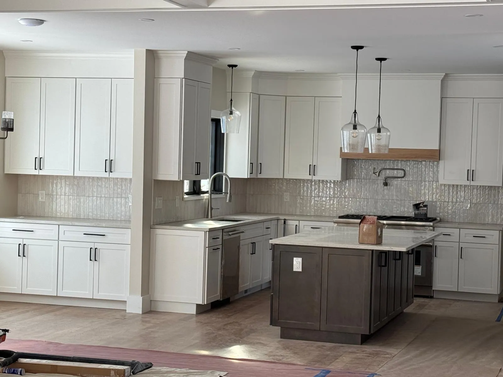 Finished kitchen with white shaker cabinets, marbled quartz counters, and pendant lighting over a center island