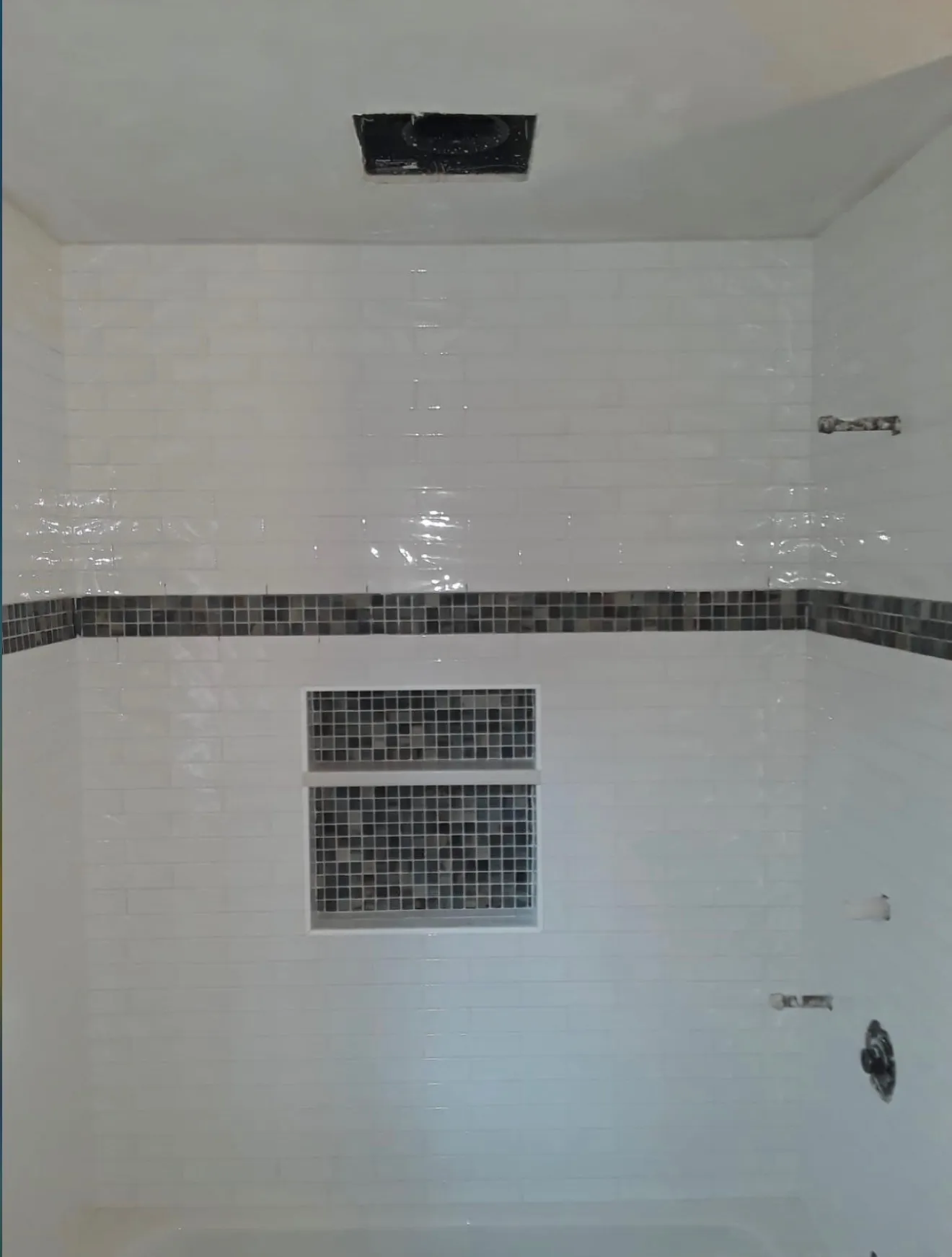 Wider view of the same white-subway shower showing the wide built-in niche