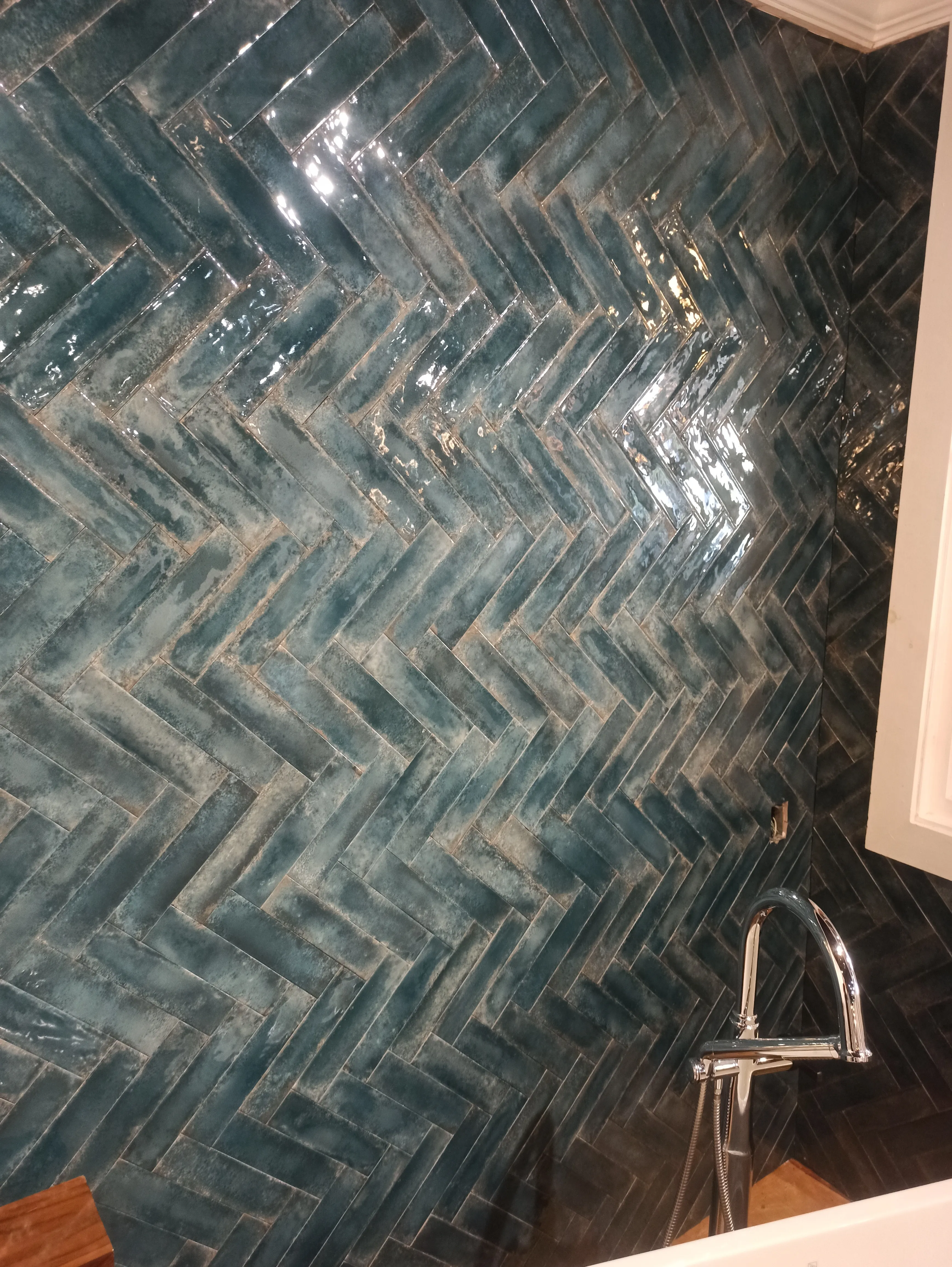 Teal herringbone tile floor in a remodeled bathroom