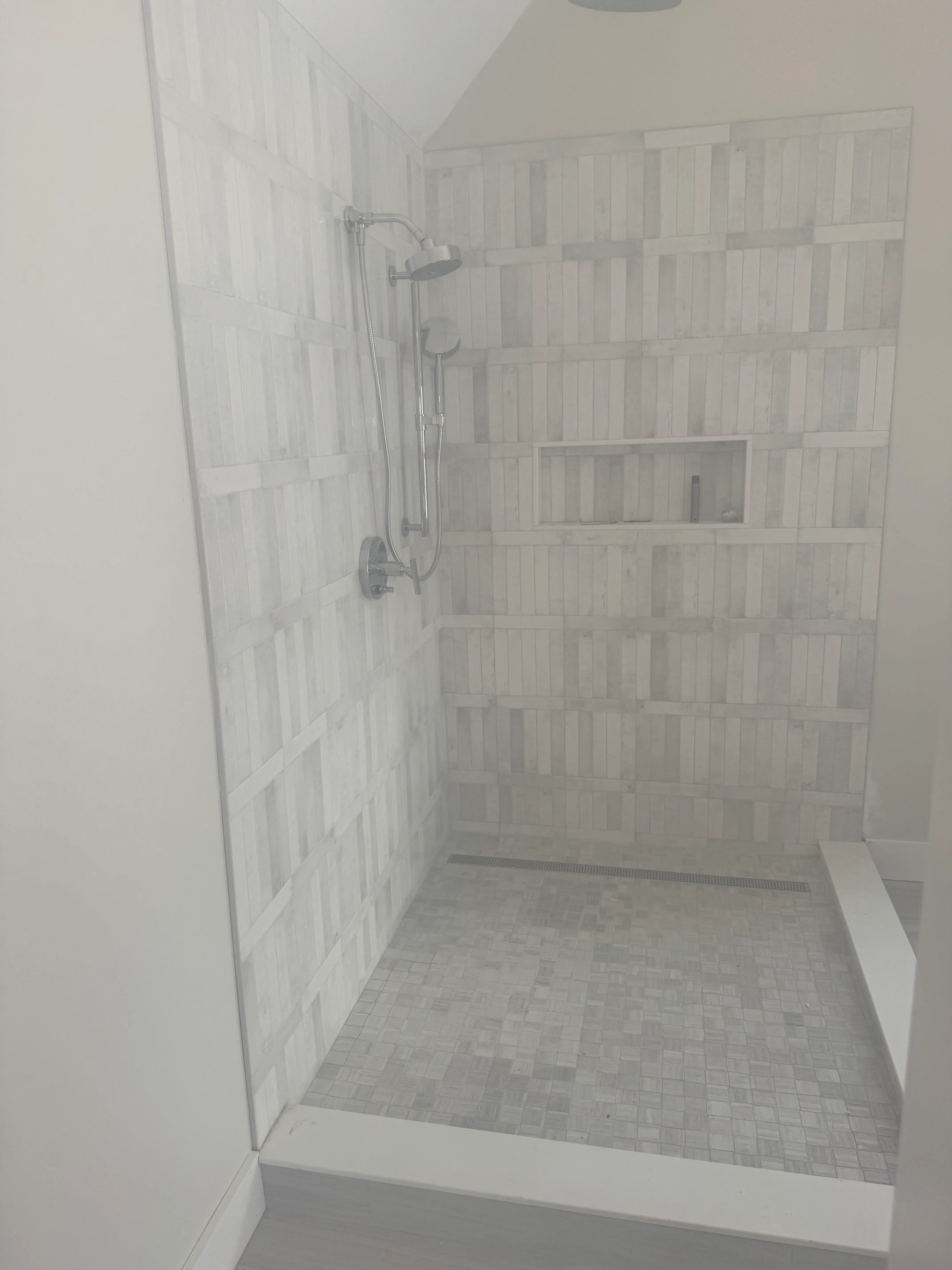 Stacked-rectangle textured tile shower wall with built-in niche