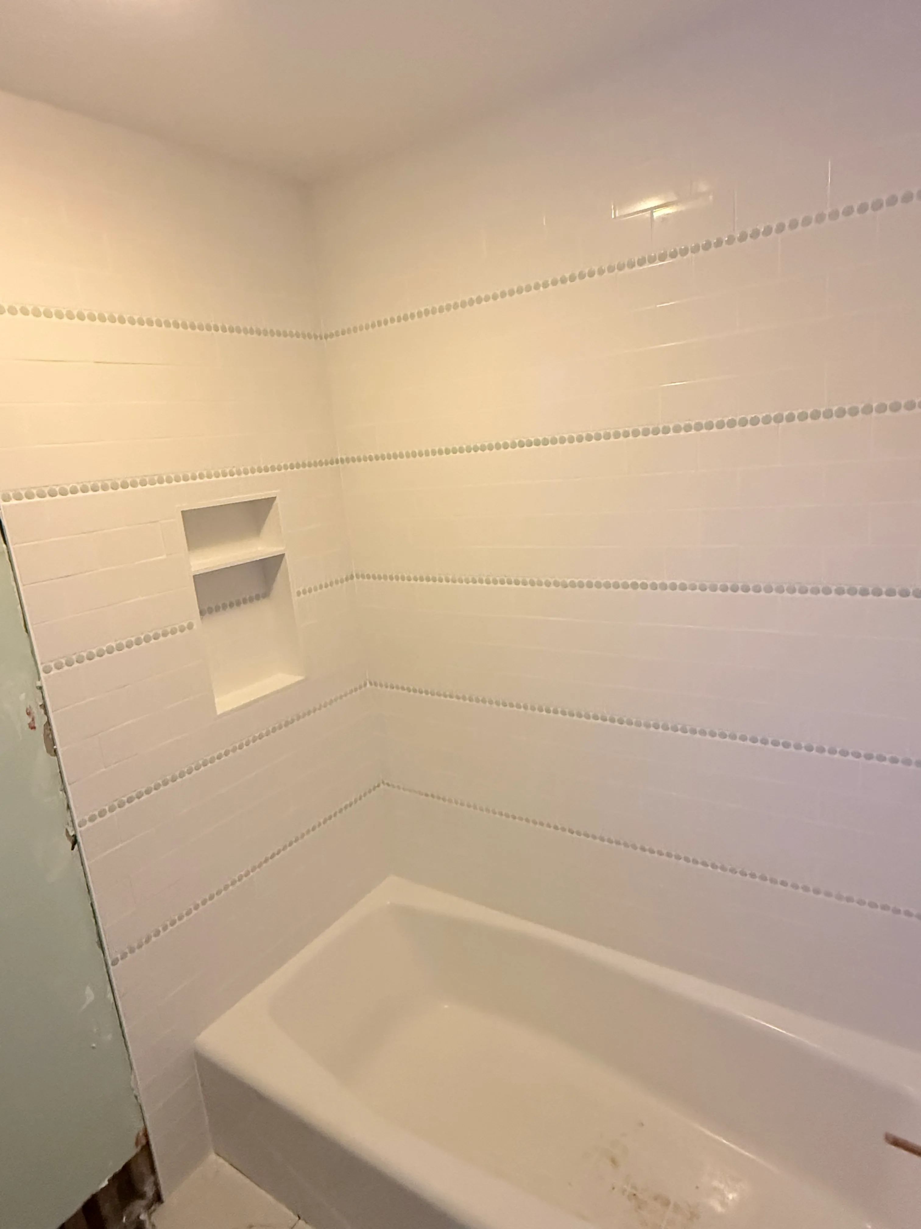 Vertical-subway shower wall with wide built-in niche, install in progress