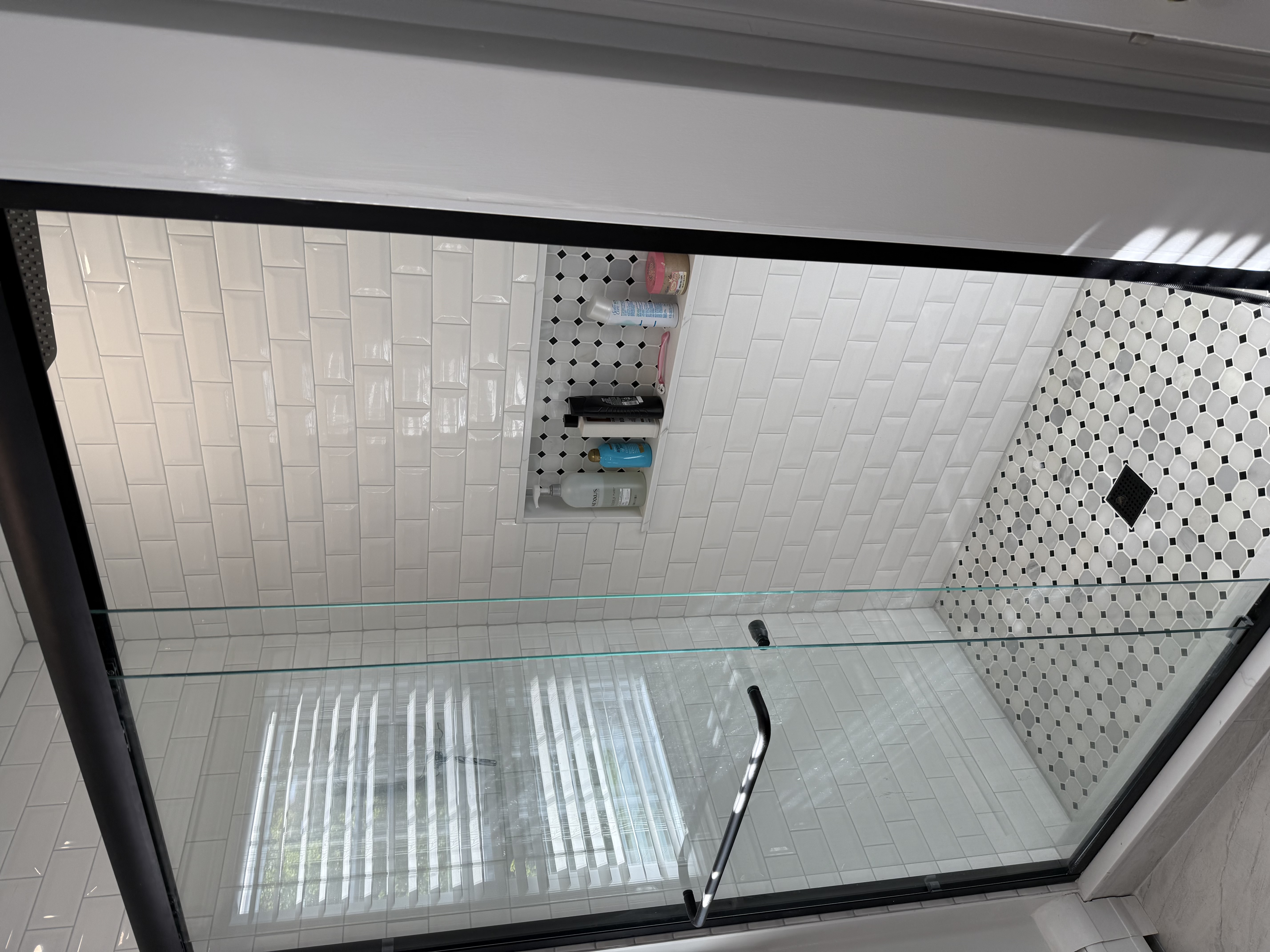 Modern black-frame glass shower with subway and penny tile
