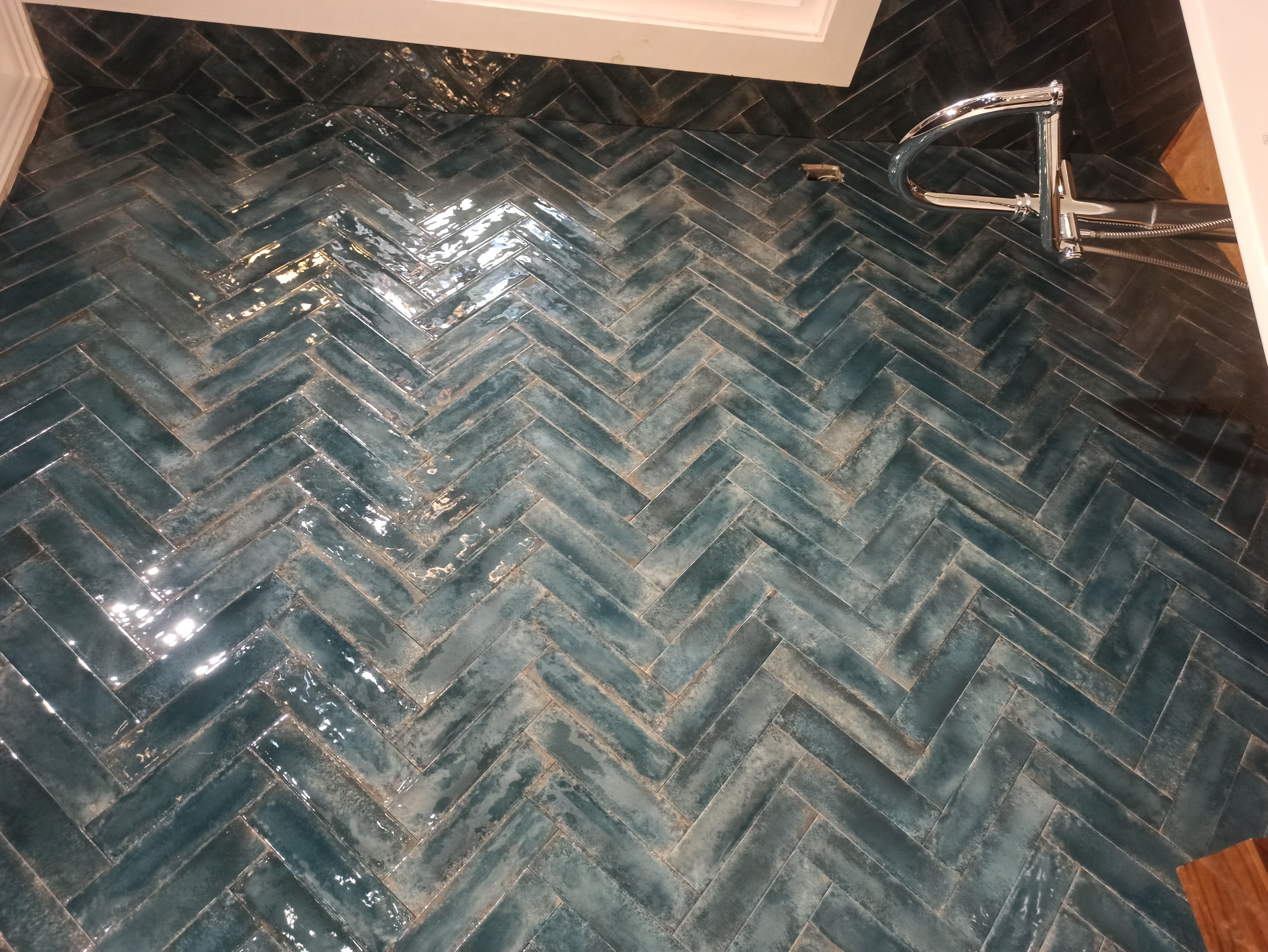 Teal herringbone tile floor installation